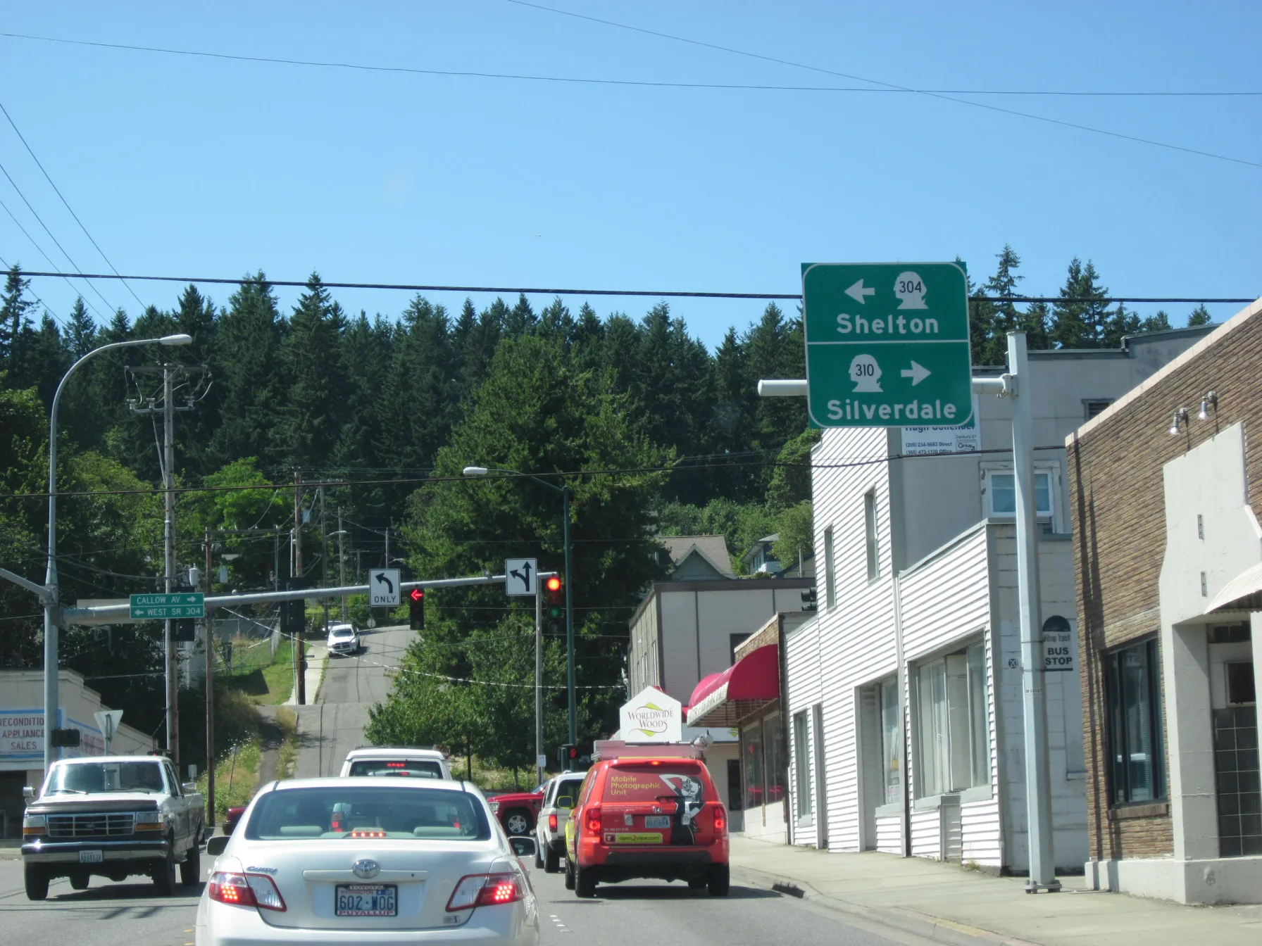 A Bremerton city street with traffic at an intersection, road signs pointing toward Shelton and Silverdale