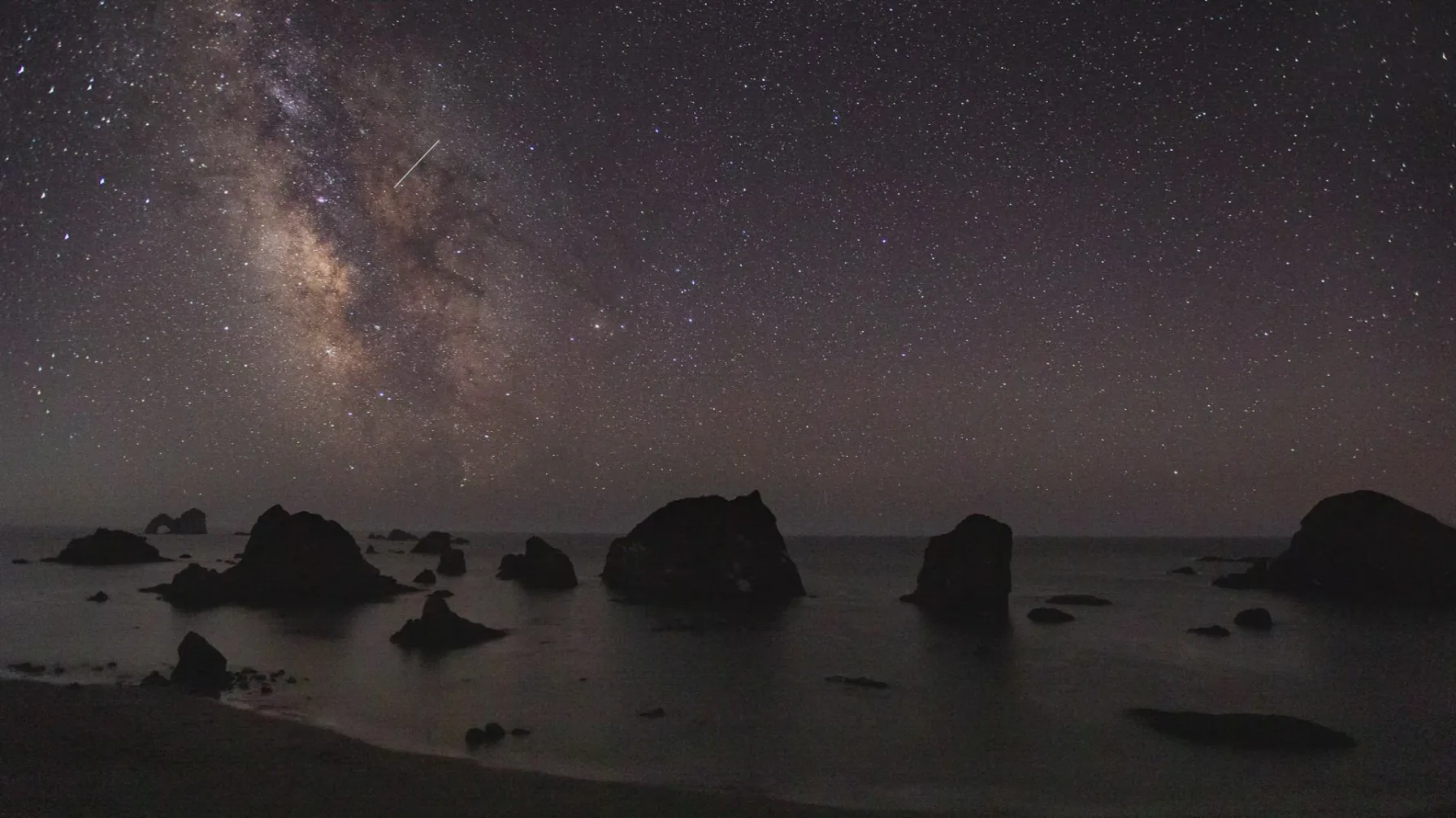 Meteors streak across a dark night sky over the Pacific Northwest coast, similar to the fireball reported over Washington on Aug. 14, 2026