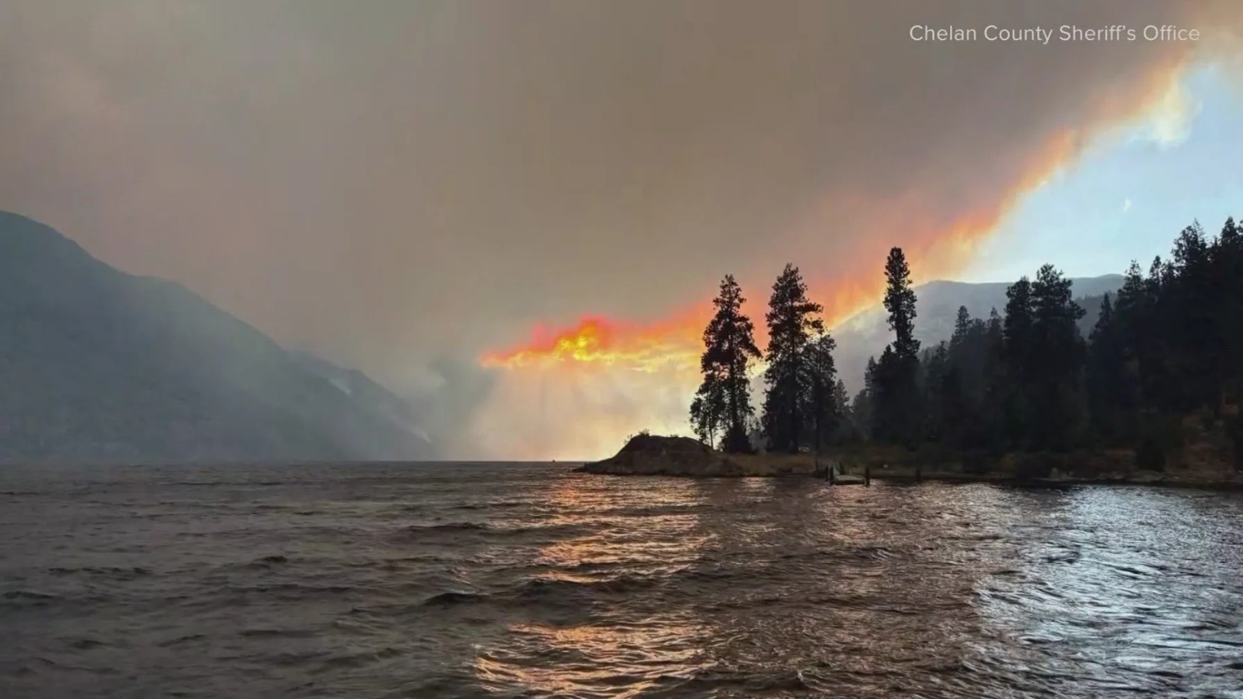 Smoke and fire glow visible across Lake Chelan at dusk as the Little Giant Fire burns near the shoreline