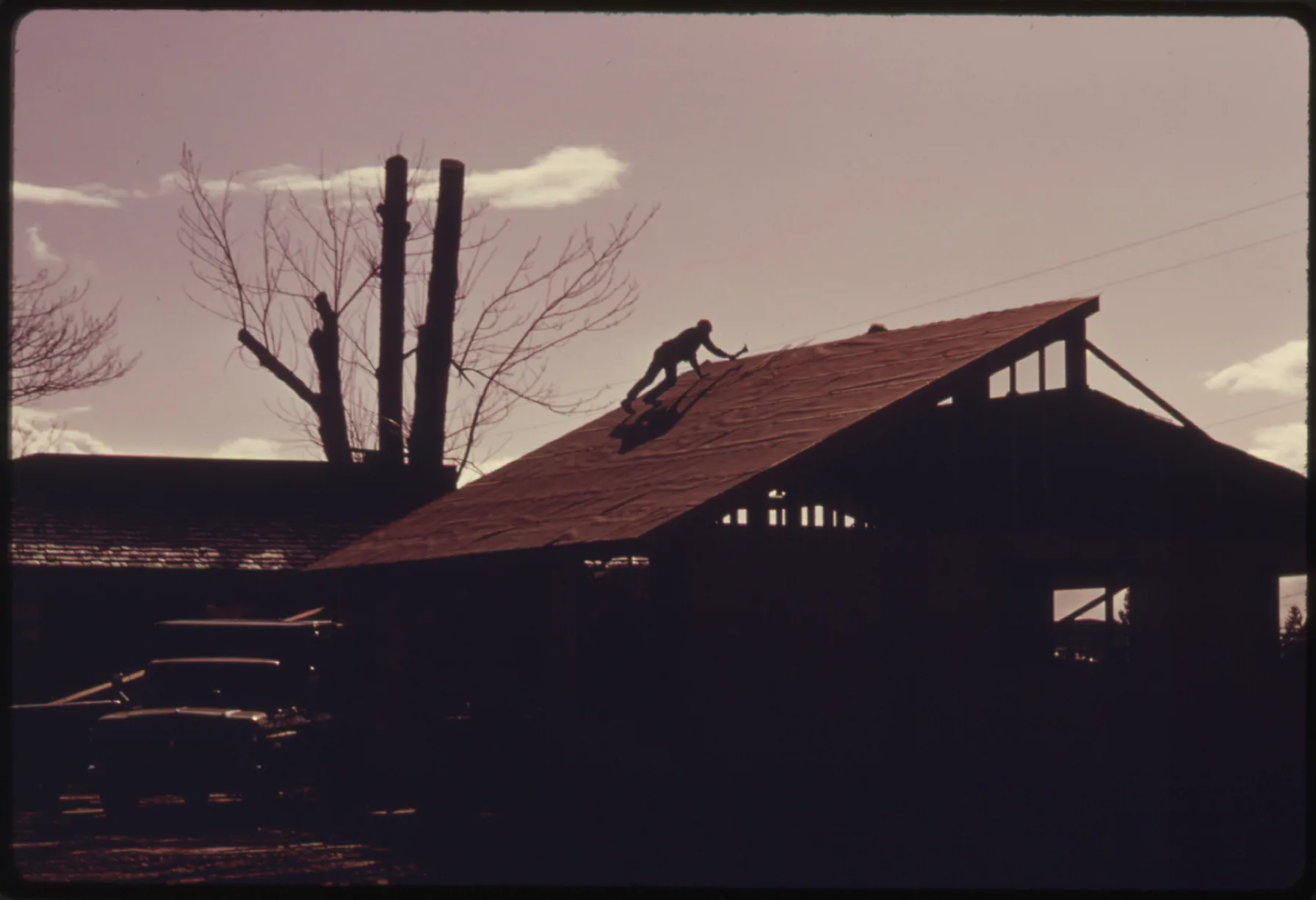 A 1975 National Archives photo shows a worker roofing a new commercial building under construction along Highway 305 near Poulsbo, Washington.