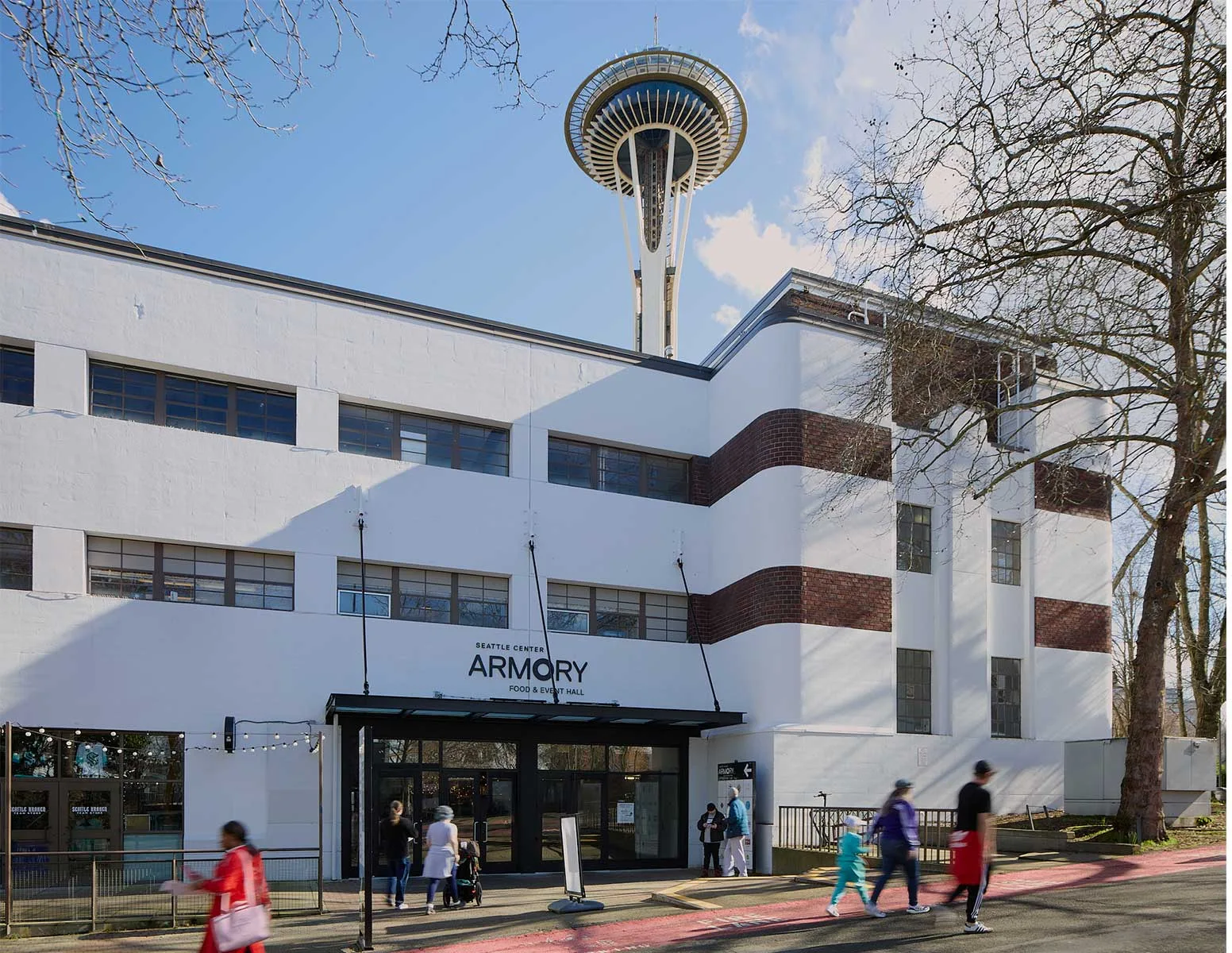 The Seattle Center Armory food and event hall with the Space Needle rising behind it on the Seattle Center campus in Seattle, Washington.
