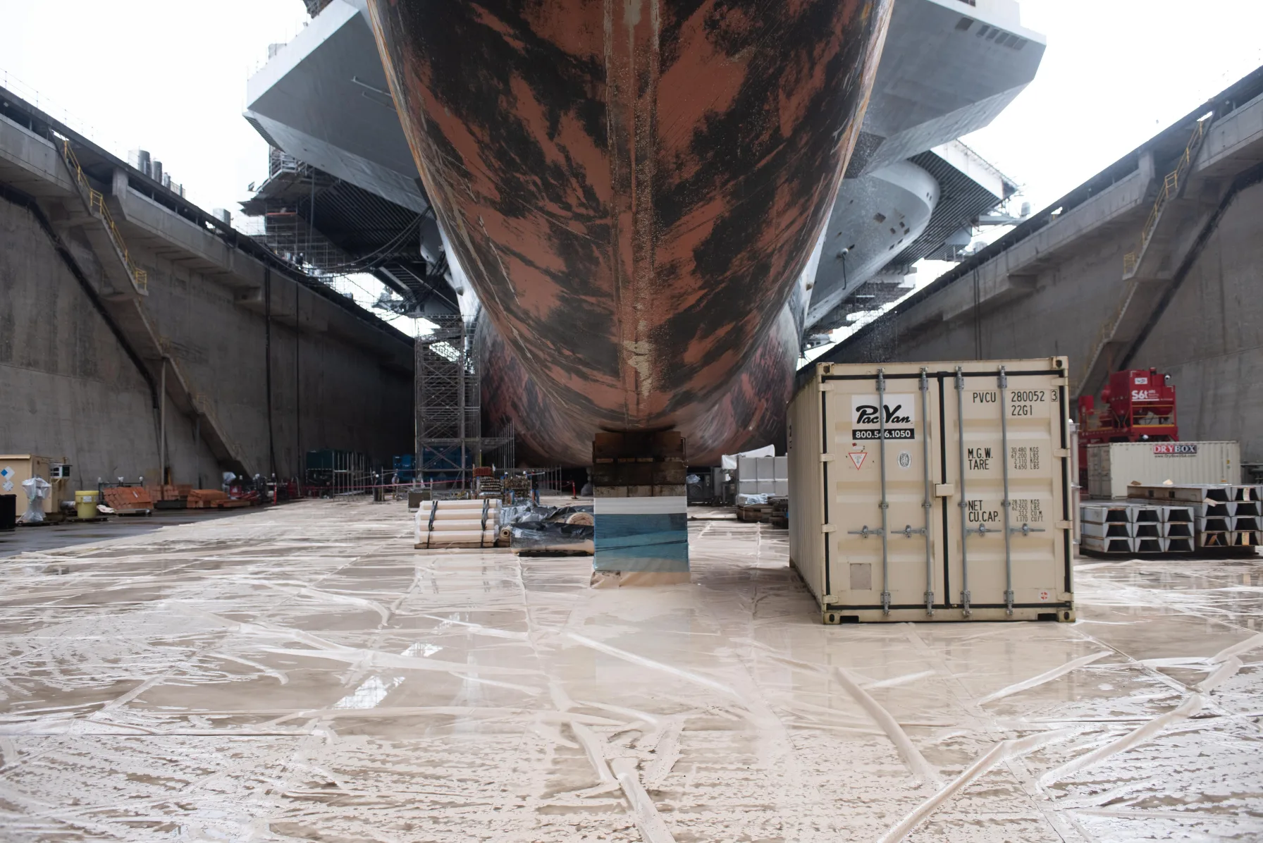 The bow of the aircraft carrier USS Ronald Reagan towers over workers in a dry dock at Puget Sound Naval Shipyard in Bremerton, Washington.