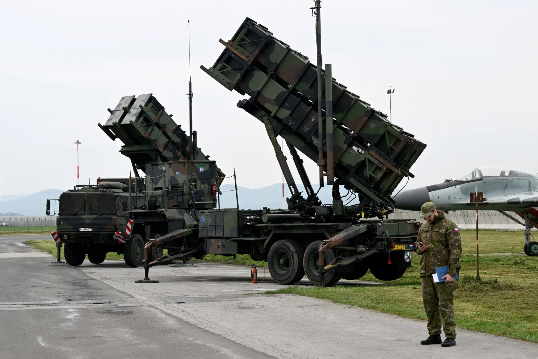 A Patriot missile air defense battery raised and ready to fire, personnel standing nearby