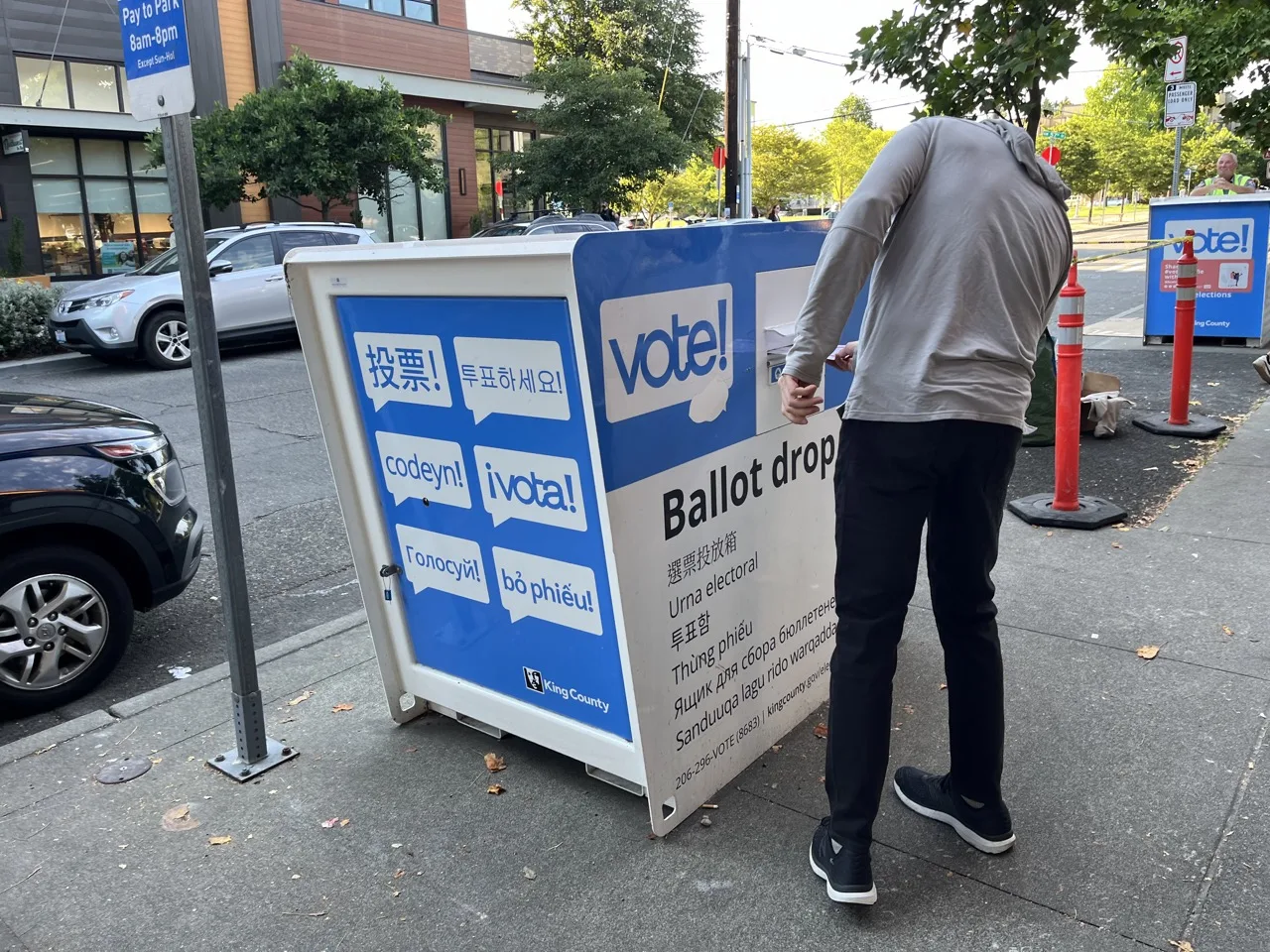 A voter drops off a ballot at a King County ballot drop box ahead of Washington's primary election.