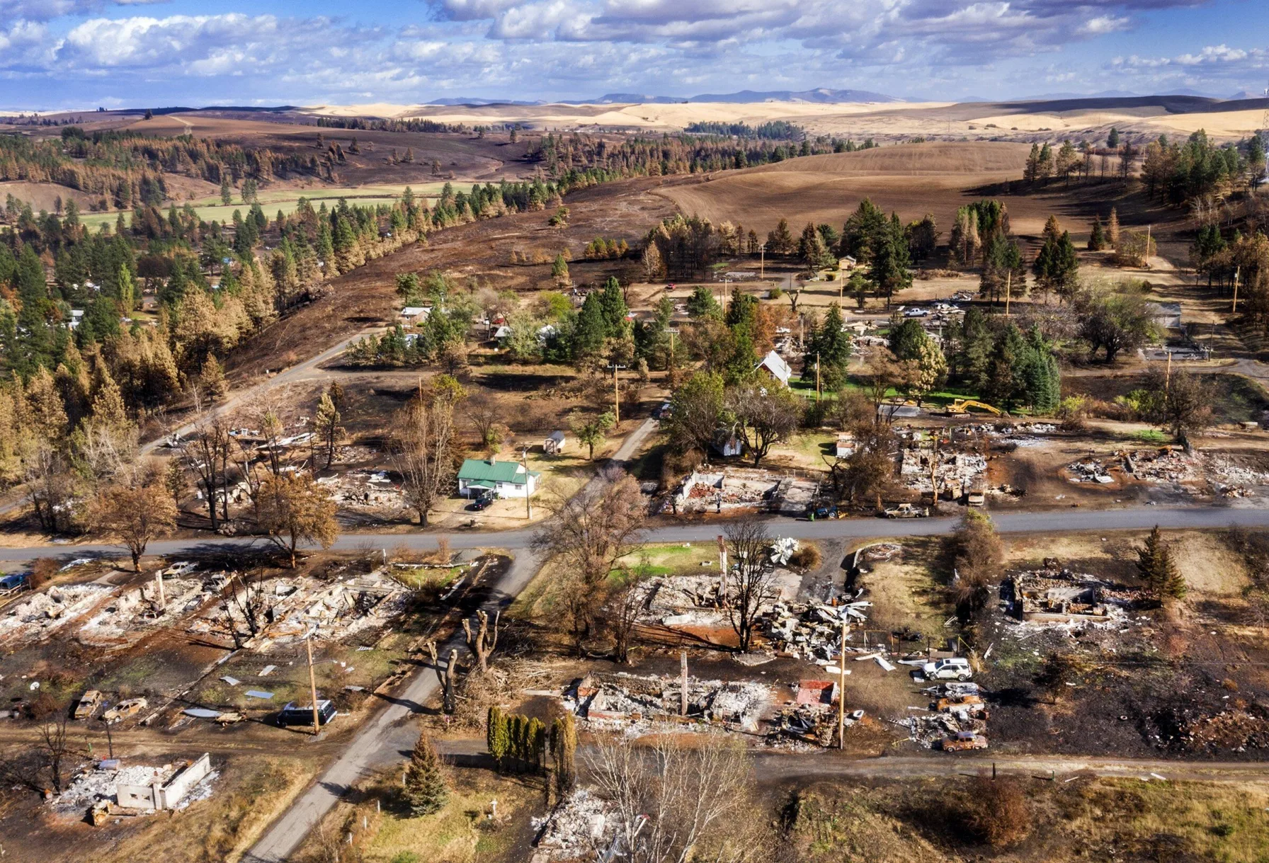 Aerial view of burned home foundations scattered among surviving trees and houses in Malden, Washington, from the 2020 Babb Road Fire that destroyed 80% of the town